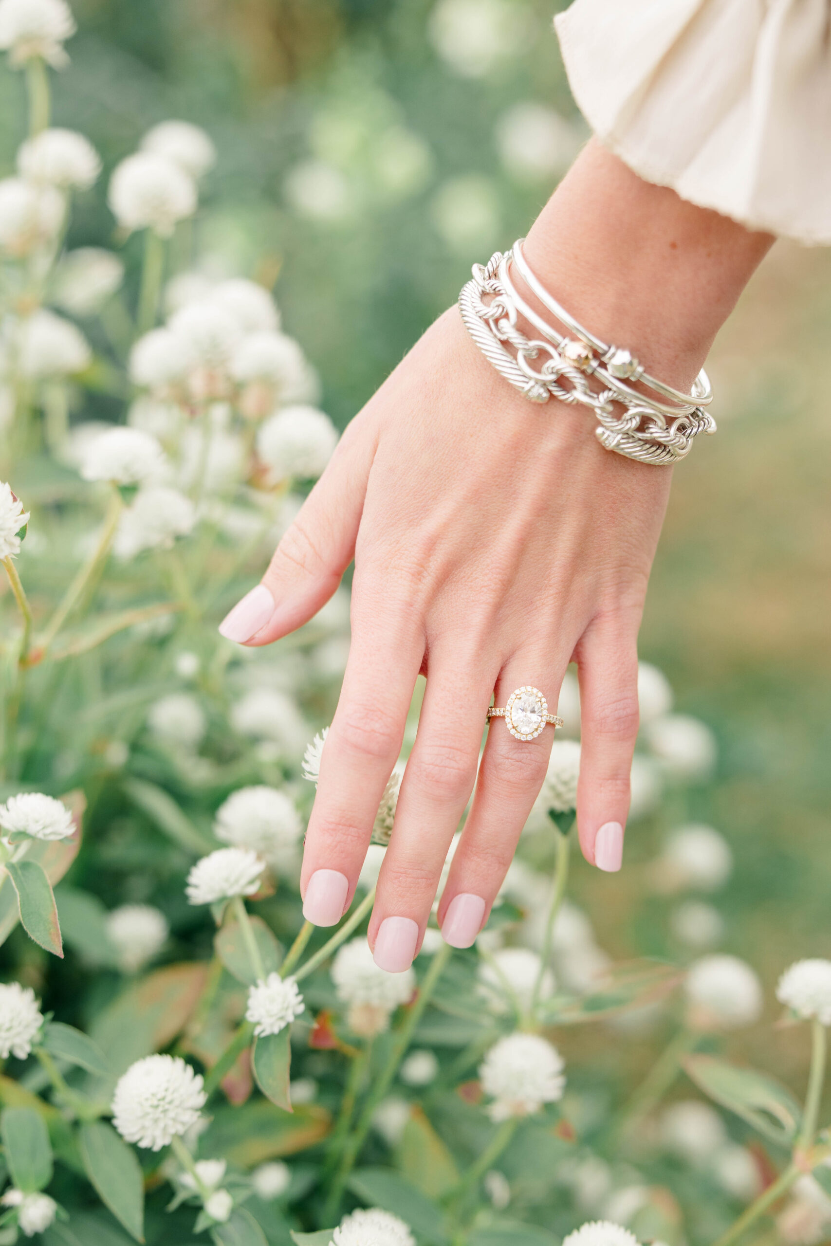 Newport Wedding Photographer and Videographer | Serving CT, RI, Massachusetts, and Surrounding New England Areas | Hand with engagement ring with some white flowers in the background