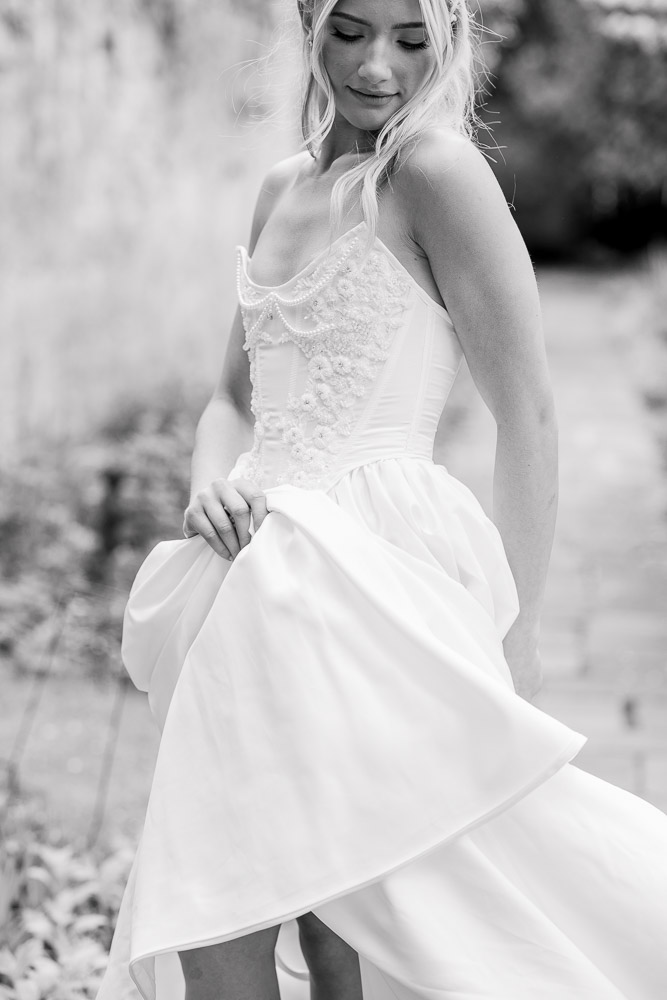 CT Wedding Photographer and Wedding Videographer | Serving Newport, RI, and New England Areas | Bride holding her tube top gown shot in black and white film-style