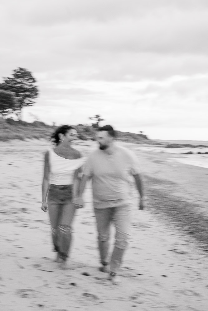Engagement Photographer Newport RI and Videographer | Serving CT, RI, and New England Areas | Couple walking on the beach in black and white film-style