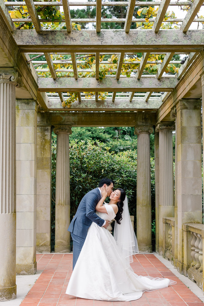Wedding Photographers in CT and Wedding Videographer | Serving Newport, RI, and New England Areas | Groom holding bride's waist while kissing her cheek