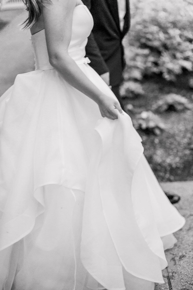 Newport Wedding Photographer and Videographer | Serving CT, RI, Massachusetts, and Surrounding New England Areas | Bride holding her gown while walking with the groom
