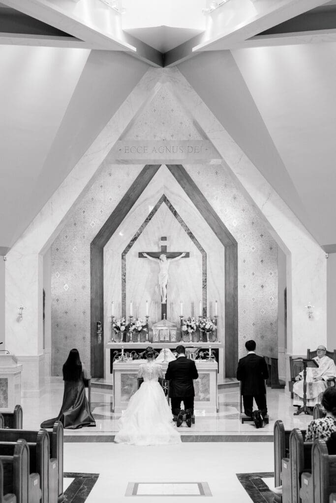 Bride and groom kneeling during a traditional estate wedding ceremony in a chapel