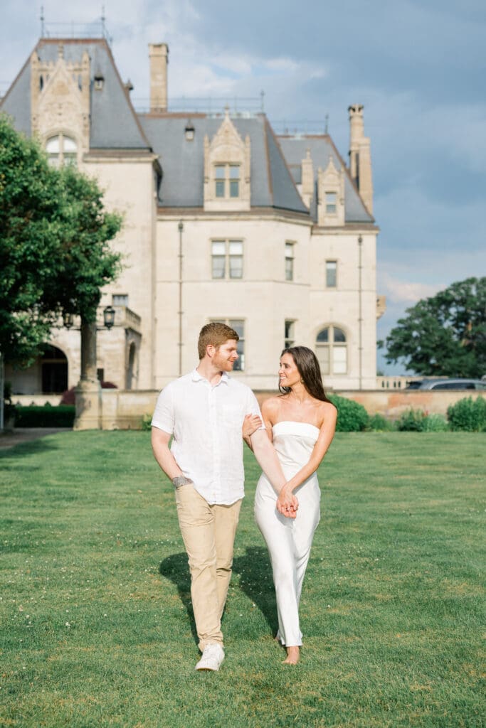 Couple walking together along a garden path at Ochre Court during a Newport engagement session.