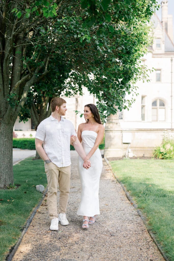 Couple walking together along a garden path at Ochre Court during a Newport engagement session.