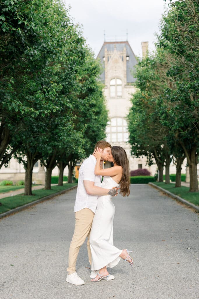 Couple kissing along the tree-lined drive at Ochre Court during a Newport engagement session.