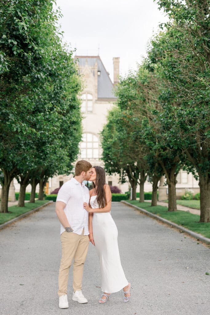 Couple kissing along the tree-lined drive at Ochre Court during a Newport engagement session.