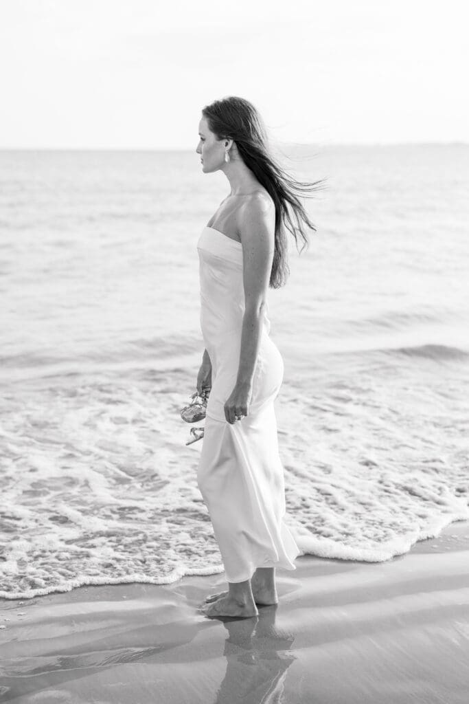Woman standing barefoot by the ocean during a Newport engagement session.