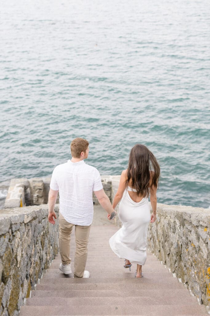 Couple walking down the stone steps at 70 Steps during a Newport engagement session overlooking the ocean.