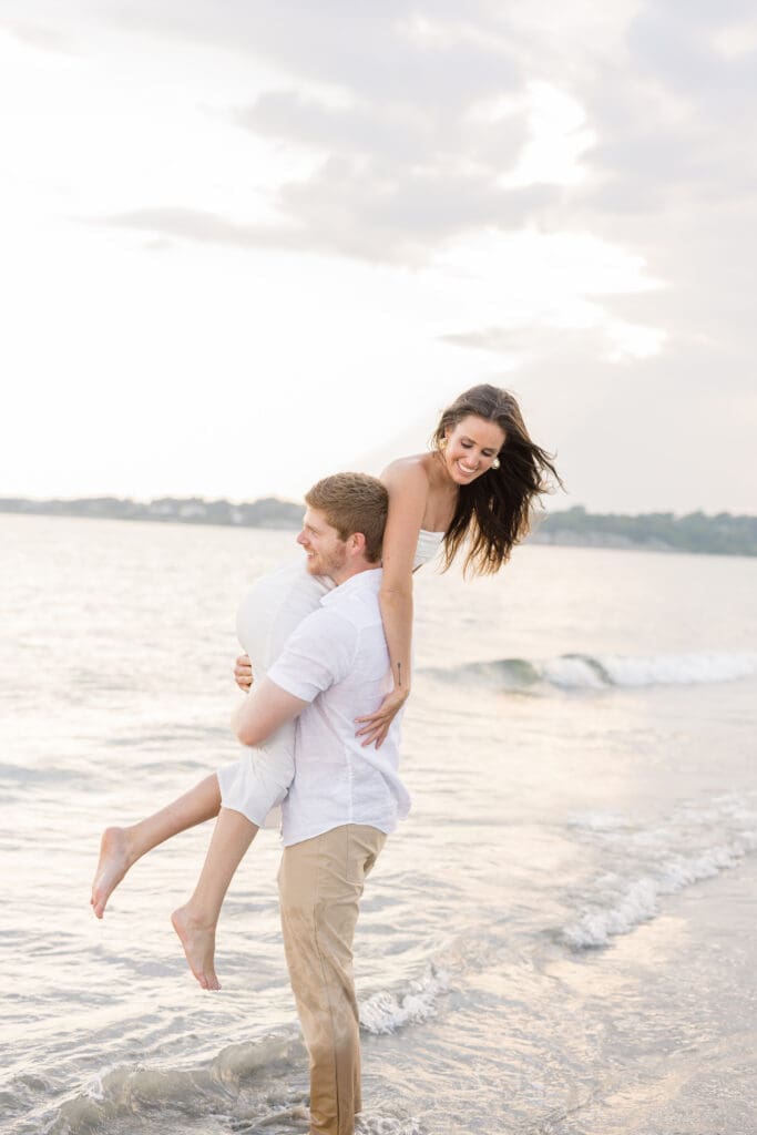 Couple laughing in the ocean during a Newport engagement session.