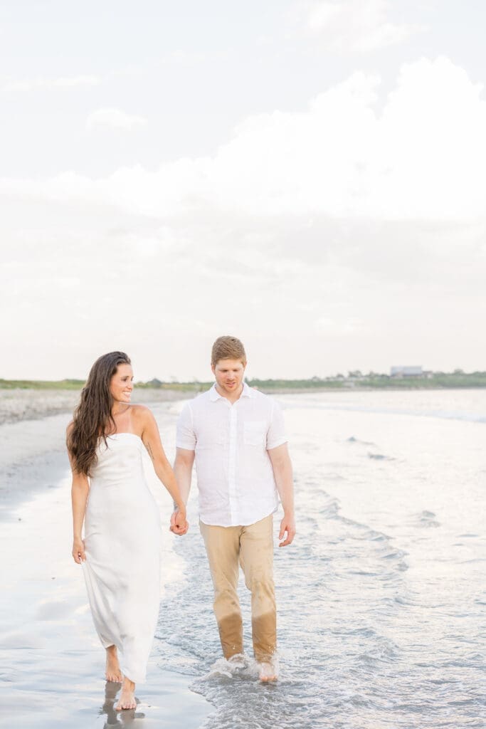 Couple walking barefoot by the ocean during a Newport engagement session.