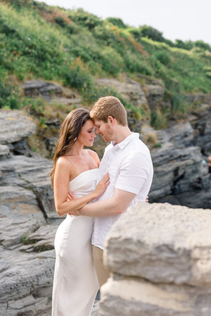 Couple embracing on the rocky cliffs at 70 Steps during a Newport engagement session overlooking the ocean