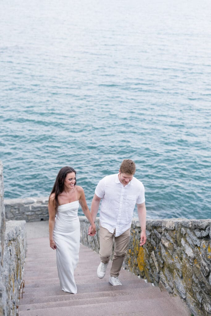 Couple walking up the stone steps at 70 Steps during a Newport engagement session overlooking the ocean.